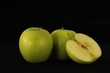 Apple or apples whole or sliced in half on black background.