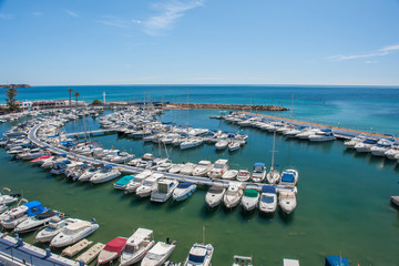 Small yachting port in Spain with the Mediterranean Sea in the background on a summer day with clear blue sky