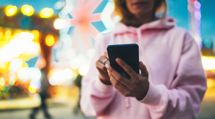 girl pointing finger on screen smartphone on defocus background bokeh light in evening street attraction, woman using in hands mobile phone gadget in city illumination, online wifi internet concept