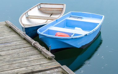 Fototapeta na wymiar 2 small rowboats tied to a wooden pier in Massachusetts with raindrops starting to fall