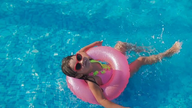 Child in the pool. A little girl in sunglasses is swimming in the pool.