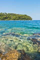 Sea rocks below surface of crystal clear turquoise water at morning in Panormos bay, island of Skopelos, Greece