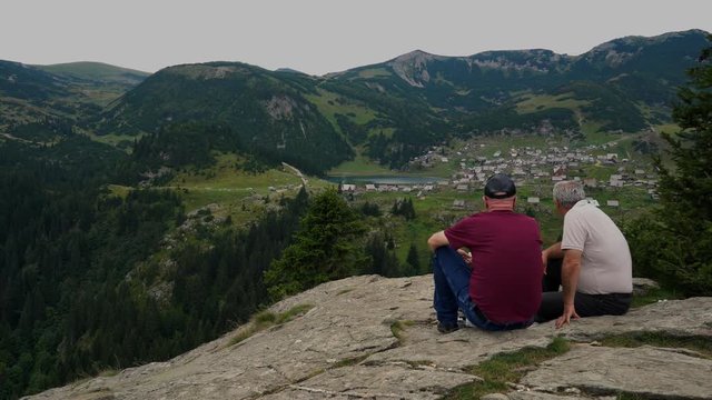 Two man looking at the lake and village in the distance - (4K)