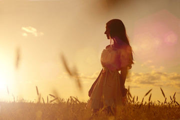Obraz premium Woman in wheat field at sunset