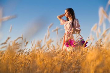 Obraz premium Woman in wheat field at sunset