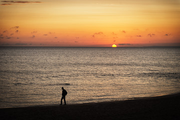 Ein Mann spaziert im Sinnenaufgang am Strand