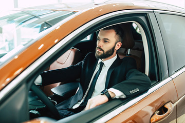 Businessman in full suit driving a new car