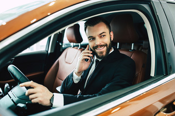 Happy businessman talking on the phone in car while driving on city