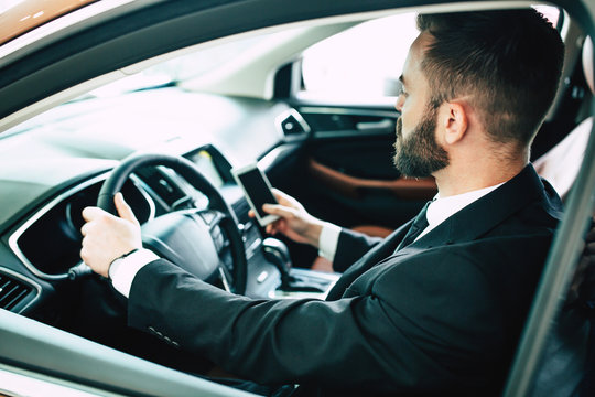 Back cropped photo of young businessman using smart phone in car