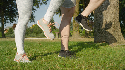 LOW ANGLE: Unrecognizable athletic couple running in place in sunny nature.