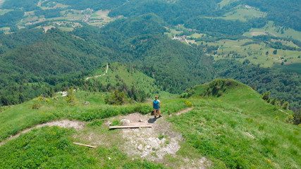 Fototapeta na wymiar AERIAL: Flying above hiker girl observing the breathtaking valley below her.