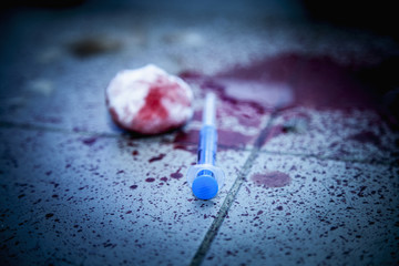 Used syringe and blood on dirty floor as symbol of narcotism and drug addiction.