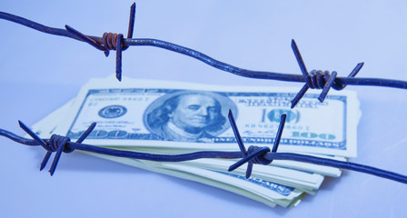 US Dollar money wrapped in barbed wire as symbol of economic warfare, sanctions and embargo busting