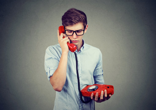 Sad worried teenager man talking on an old fashioned telephone