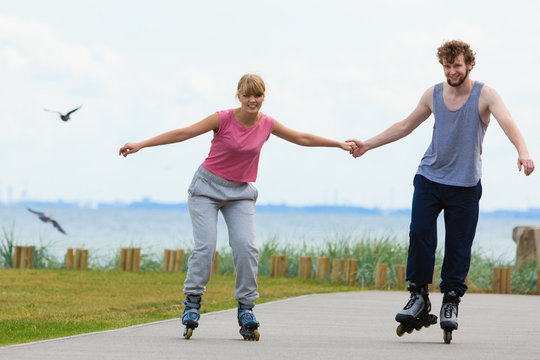 Young couple holding hands while rollerblading