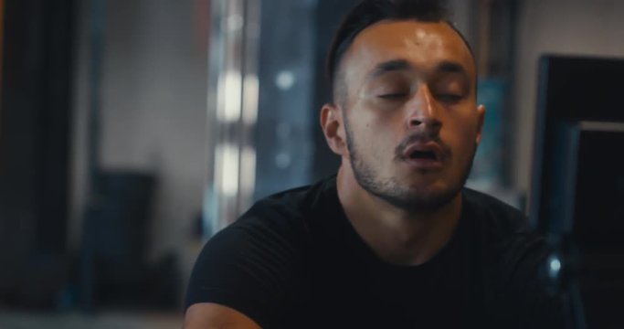 CU portrait of Caucasian male athlete working out in a gym, using rowing ergometer indoors. 4K UHD