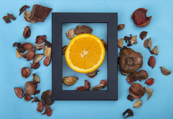 Half orange with black frame and dry flowers decoration on blue background