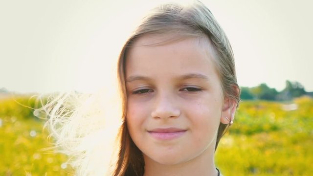 Portrait of attractive little girl with a big brown eyes on nature background with developing hair