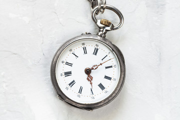 old pocket watch on light gray plaster surface