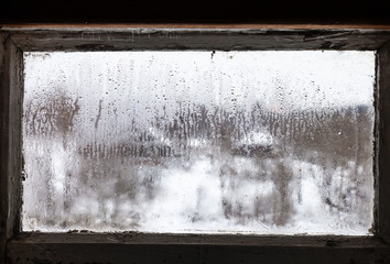 water drops on misted frozen window of rural house