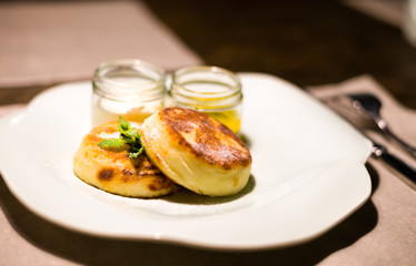 cheesecakes with honey and sour cream on a white plate