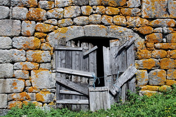 Ancienne porte et mur en pierre avec lichen orange