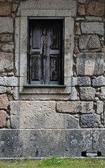 Fototapeta na wymiar Janela velha em madeira velha numa parede construida em pedra de uma casa antiga
