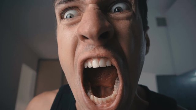 Angry man screaming and threatening with violence at home in the kitchen.