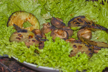 Grilled eggplant and champignon mushrooms lie on a green salad
