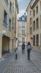 Two men walking down historic, narrow, cobbled street in Northern France