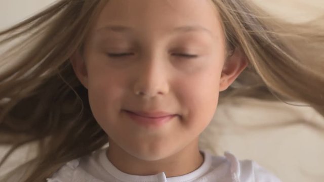 Close Up Portrait of happy young  girl with blue eyes and blond hair. Standing on Wind. Breeze is playing with girl's hair. Stormy weather, autumn, winter, spring. Old style vintage. Shallow focus