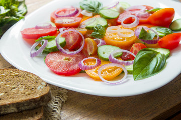 Sliced heirloom tomatoes, crisp cucumbers with chopped red onion, chives drizzled with olive oil and added basil leaves.