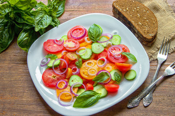 Sliced heirloom tomatoes, crisp cucumbers with chopped red onion, chives drizzled with olive oil and added basil leaves.
