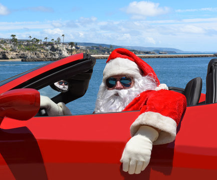 Santa Claus sitting in his red sports car at the beach