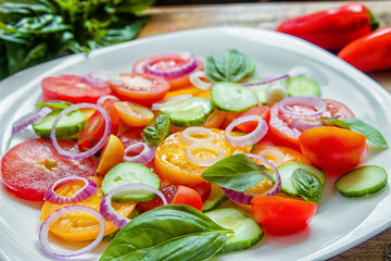 Sliced heirloom tomatoes, crisp cucumbers with chopped red onion, chives drizzled with olive oil and added basil leaves.
