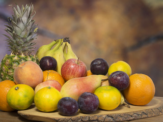 fruit on wooden table, pineapple orange, pear, mandarin, banana, plum, apple and peach