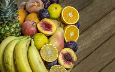 fruit on wooden table, pineapple orange, pear, mandarin, banana, plum, apple and peach