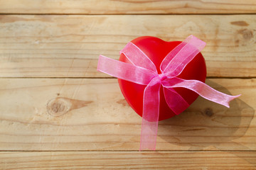 A red heart with bow on plank