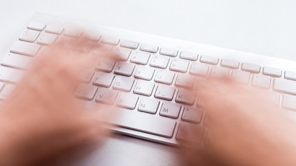 Blurred hand typing on keyboard