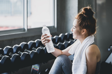 Fitness woman drinking water in gym