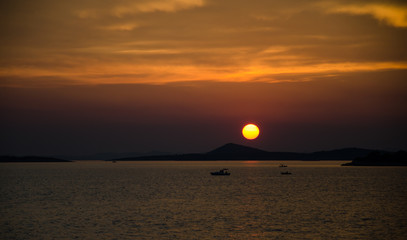 Romantic sunset over sea with boats in distance