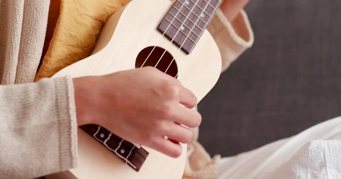 Woman practice ukulele at home