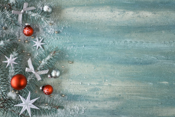 Christmas background with fir twigs, light green and red trinkets and silver stars on light...