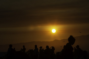 Silhouettes of the people during the sunset over Santa Monica beach in California