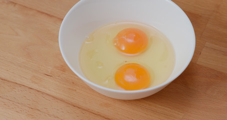 Breaking egg in glass bowl