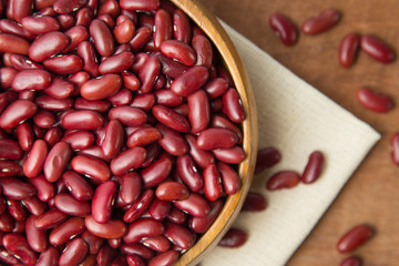 Red beans in wooden bowl putting on linen and wooden background.