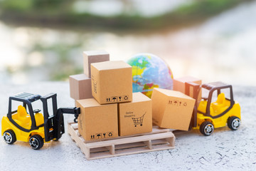 Mini forklift truck load cardboard box with shopping cart symbol on wooden pallet and globe near...