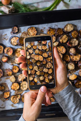 Woman hands make smartphone food photography of roasted eggplants slices. Trendy phone food photo for social media or blogging. Vegan lunch, vegetarian dinner, healthy diet. Top view