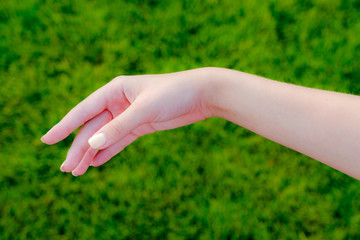 Female hand against a background of green grass