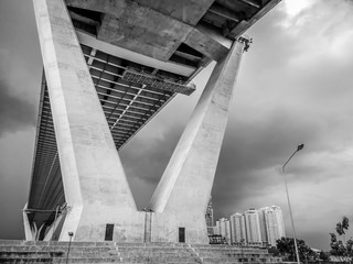 Low angle view of huge and stately bridge with strong pillar with cloudy sky and tower in the background, urban and futuristic concept, Bhumibol Bridge, Bangkok, Thailand - Powered by Adobe